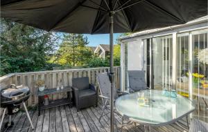 Cozy Apartment In Rm With Kitchen في رومو كيركيبي: طاولة زجاجية وكراسي على سطح مع مظلة