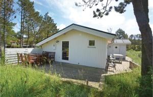 a white cottage with a wooden deck in a field at Holiday Home Sandtornvej Thisted V in Sønder Vorupør