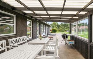 a porch with white benches and tables and windows at Holiday Home Egelunden Oksbøl Ii in Oksbøl +29 photos