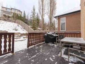 una terrazza in legno con tavolo e neve di 2500 sq house in Springbank Hill BL 261818 a Calgary