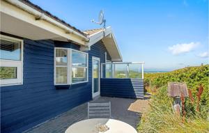 a blue house with a table and a chair at Pynten in Grønhøj