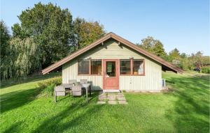 a small house with a table and chairs in the grass at Amazing Home In Kirke Hyllinge With Kitchen in Sæby