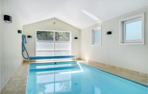 einen Pool in einem weißen Zimmer mit blauen Sitzgelegenheiten in der Unterkunft Cozy Home In Gilleleje With Indoor Swimming Pool in Gilleleje