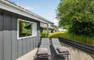 a deck with four chairs and a window at Blåmejsen in Snogebæk
