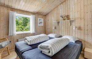 two beds in a room with wooden walls and a window at Blåmejsen in Snogebæk