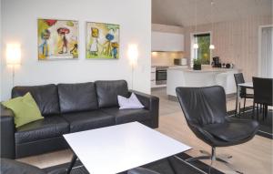 un soggiorno con divano nero e tavolo bianco di Three-Bedroom Holiday Home In Blavand a Blåvand