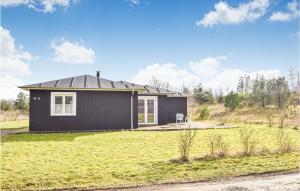 una pequeña casa negra en un campo de hierba en Gorgeous Home In Ejstrupholm With Wifi, en Ejstrup
