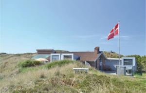 a house on top of a hill with a flag at 3 Bedroom Cozy Home In Hvide Sande in Havrvig