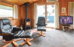 a living room with two chairs and a stove at Holiday Home Fyrmarken Hvide Sande Vi in Nørre Lyngvig