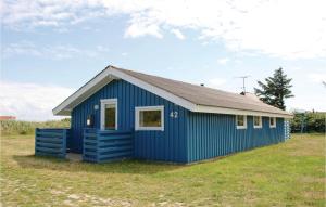 een blauwe schuur op een grasveld met een hemel bij Awesome Home In Hvide Sande With Kitchen in Nørre Lyngvig