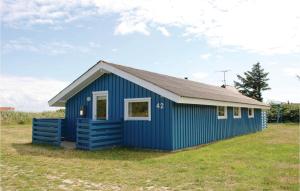 a blue shed on a grass field with a sky at Holiday Home Fyrmarken Hvide Sande Vi in Nørre Lyngvig