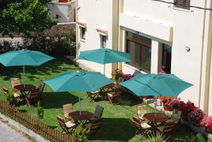 a group of tables and chairs with blue umbrellas at Aptera Hotel in Megála Khoráfia