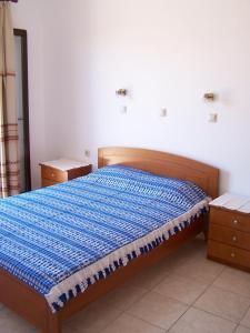 a bed with a blue comforter in a bedroom at Aptera Hotel in Megála Khoráfia