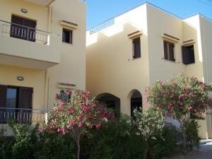 two buildings with flowering trees in front of them at Aptera Hotel in Megála Khoráfia