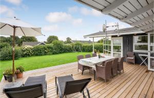 una terraza de madera con mesa, sillas y sombrilla en Stunning Home In Hejls With House Sea View, en Hejls