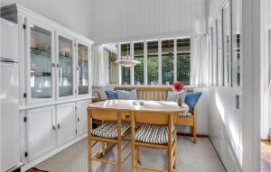 una cocina con armarios blancos y una mesa y sillas de madera. en Awesome Apartment In Allinge With Kitchen, en Allinge