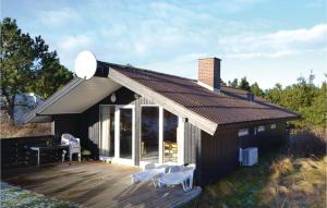 BjerregårdにあるAmazing Home In Hvide Sande With Kitchenの白い椅子が置かれた小さな黒い家