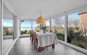 a dining room with a table and some windows at Beach Front Home In Vggerlse With House Sea View in Væggerløse