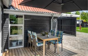 a wooden table with chairs and an umbrella on a deck at Stunning Home In Sjællands Odde in Yderby