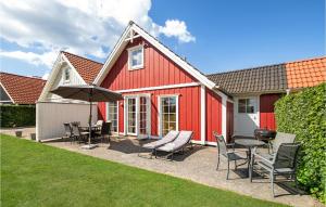 a red house with chairs and tables and an umbrella at Holiday Home Strandgårdsvej Brenderup Fyn Denm in Bro