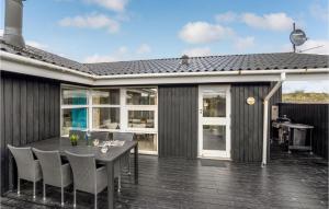 BjerregårdにあるNice Home In Hvide Sande With 3 Bedrooms, Sauna And Wifiの家の上にテーブルと椅子付きのデッキ