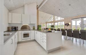 ボーゲンセにあるAwesome Home In Bogense With 6 Bedrooms, Wifi And Indoor Swimming Poolの白いキャビネット付きのオープンキッチン、ダイニングルーム