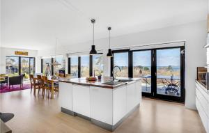 cocina con armarios blancos y comedor con mesa en 4 Bedroom Beautiful Home In Knebel, en Knebel