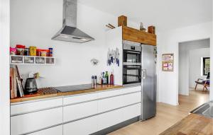 Una cocina con gabinetes blancos y un refrigerador de acero inoxidable. en 4 Bedroom Beautiful Home In Knebel, en Knebel