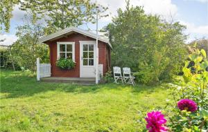 un piccolo capanno rosso con due sedie in un cortile di Holiday Home Svalevej Brenderup Fyn Iv a Skovs-Højrup Altre 18 foto