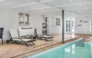 エーベルトフトにあるBeautiful Home In Ebeltoft With 8 Bedrooms, Wifi And Indoor Swimming Poolの家の隣に椅子2脚が備わるスイミングプール