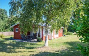 a red cabin with a tree in the yard at Awesome Home In Grenaa With 2 Bedrooms in Grenå