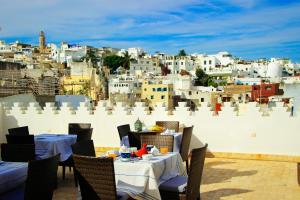 ein Restaurant mit Tischen und Stühlen vor einer Stadt in der Unterkunft Dar Souran in Tangier