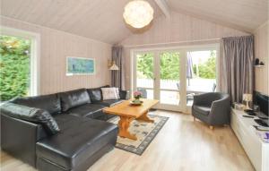 a living room with a black leather couch and a table at Holiday Home Gråpilevej in Bøtø By