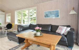 a living room with a black leather couch and a wooden table at Holiday Home Gråpilevej in Bøtø By