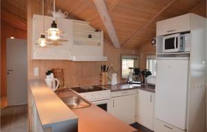 Il comprend une cuisine équipée d'appareils électroménagers blancs et d'un réfrigérateur blanc. dans l'établissement 4 Bedroom Nice Home In Idestrup, à Bøtø By