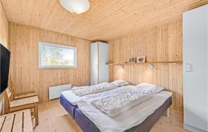1 dormitorio con 1 cama y pared de madera en Awesome Home In Rudkbing With 5 Bedrooms, Sauna And Wifi, en Spodsbjerg