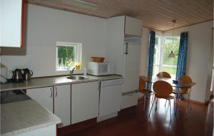 cocina con armarios blancos, mesa y microondas en Beautiful Home In Juelsminde With 3 Bedrooms And Sauna, en Sønderby