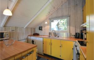 エーベルトフトにあるAmazing Home In Ebeltoft With 3 Bedroomsのキッチン(黄色のキャビネット、シンク付)