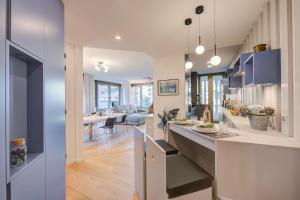 uma cozinha em plano aberto e sala de estar com armários azuis em Dandy House Few Min From Lake - Happy Rentals em Lugano