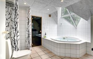 a bathroom with a tub and a toilet and a sink at Four-Bedroom Holiday Home In Norre Nebel in Nørre Nebel