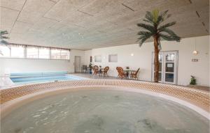 a swimming pool in a house with a palm tree at Foldingbro Kro in Lintrup