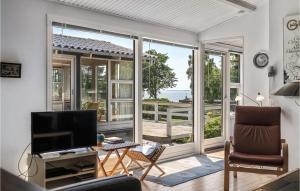 un salon avec des portes coulissantes en verre et une télévision dans l'établissement Amazing Home In Ebeltoft With Wifi, à Ebeltoft