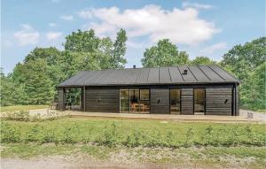 una pequeña casa con un techo negro en un campo en Four-Bedroom Holiday Home In Glesborg, en Glesborg