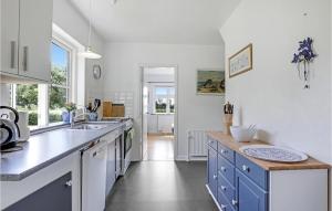 a kitchen with white walls and blue cabinets at Lovely Home In Rnne With Wifi in Rønne