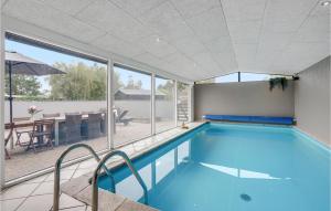 a swimming pool with a view of a patio and a table at Amazing Home In Knebel With 3 Bedrooms, Wifi And Indoor Swimming Pool in Skødshoved Strand