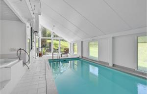 a swimming pool in a house with a tub and windows at Gorgeous Home In Ebeltoft With House A Panoramic View in Ebeltoft
