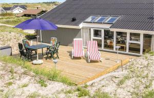 BjerregårdにあるGorgeous Home In Hvide Sande With Wifiの木製デッキ(テーブル、椅子、パラソル付)