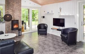 a living room with two chairs and a tv and a fireplace at Awesome Home In Tranekr With 4 Bedrooms And Sauna in Hou