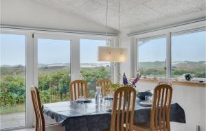 a dining room with a table and chairs and windows at Nice Home In Hvide Sande With Kitchen in Havrvig