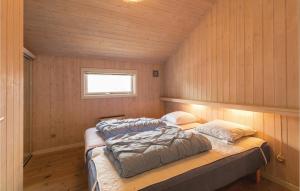 two beds in a room with wooden walls and a window at Holiday Home Tørveskæret Nexø Xii in Snogebæk